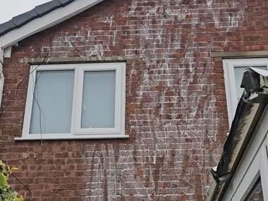 A brick gable being soft washed from a pole