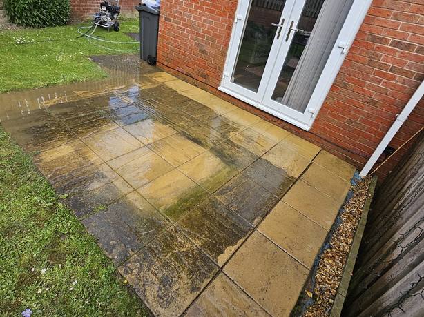 Sandstone patio part way through being pressure washed