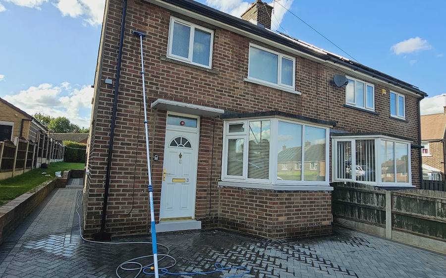 A house frontage being soft washed with the pole and hose set up